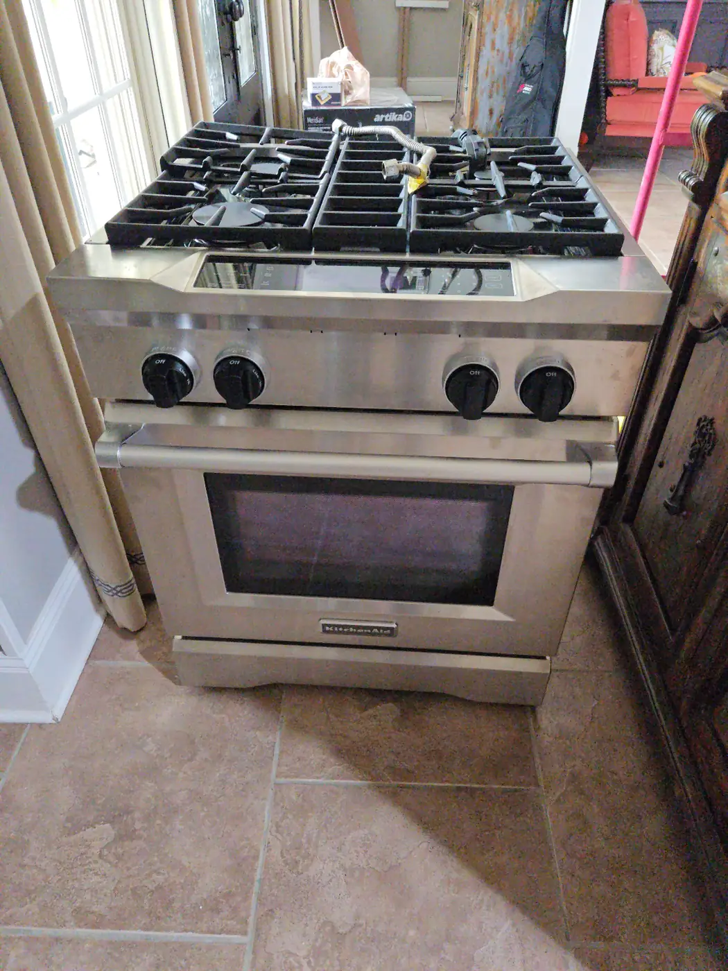 Old stainless steel gas stove pulled out and staged for appliance removal