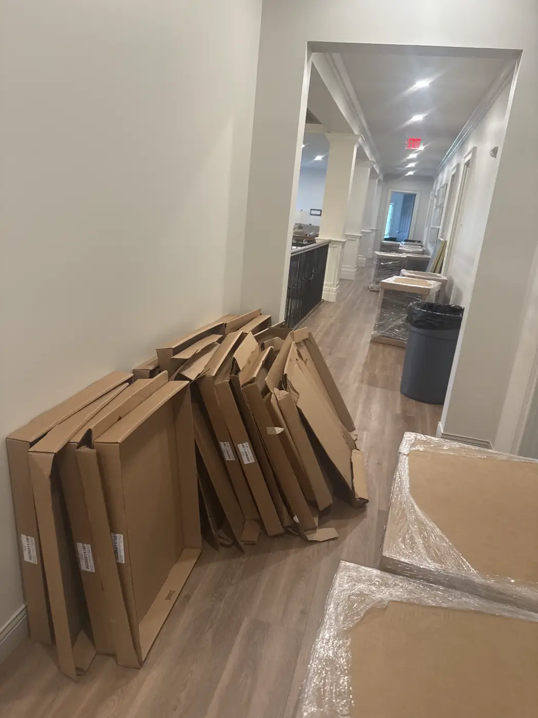 Flattened moving boxes stacked against a hallway wall during an office cleanout