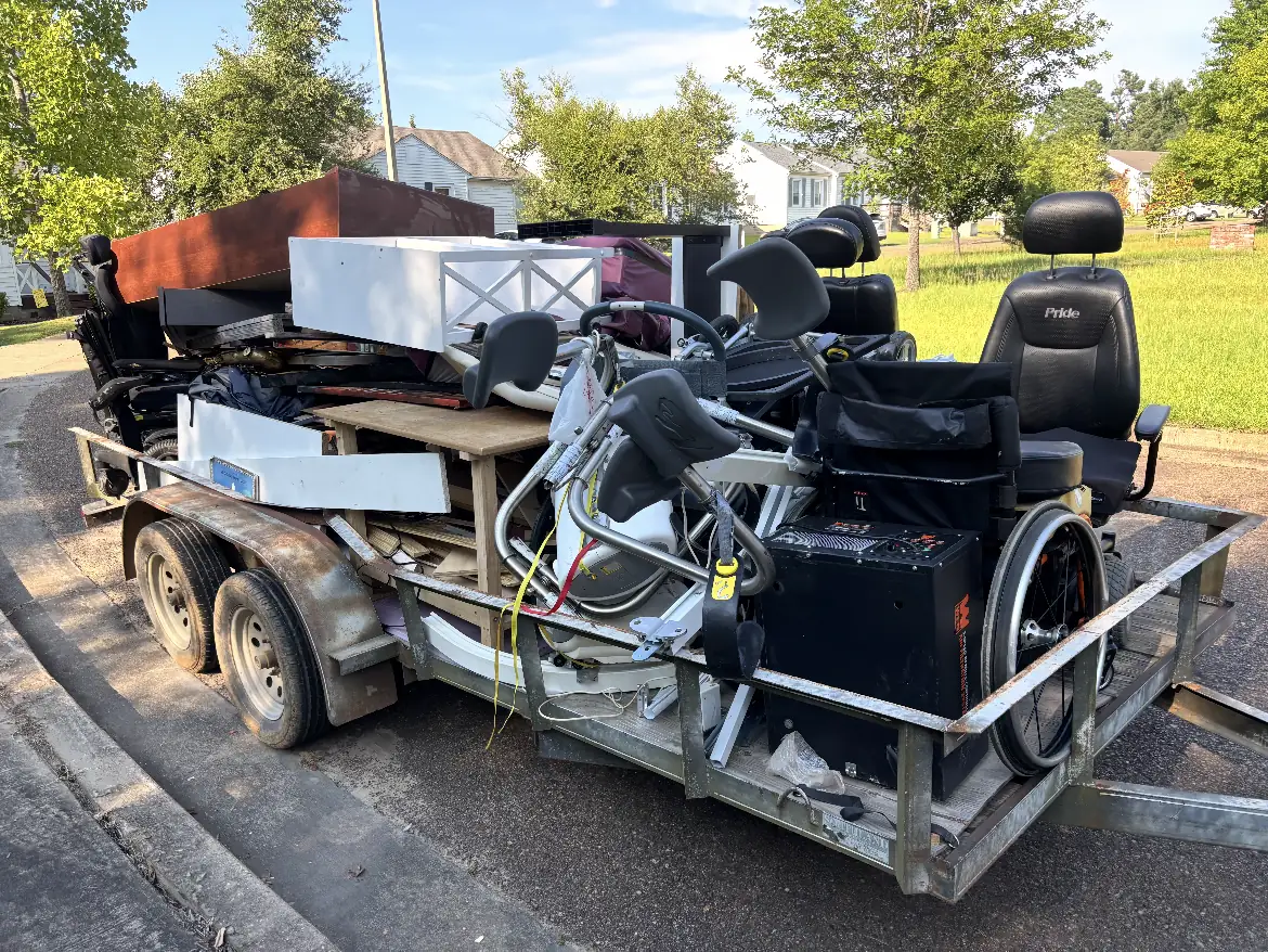 Trailer loaded with office furniture and mobility equipment at a residential curb during a cleanout